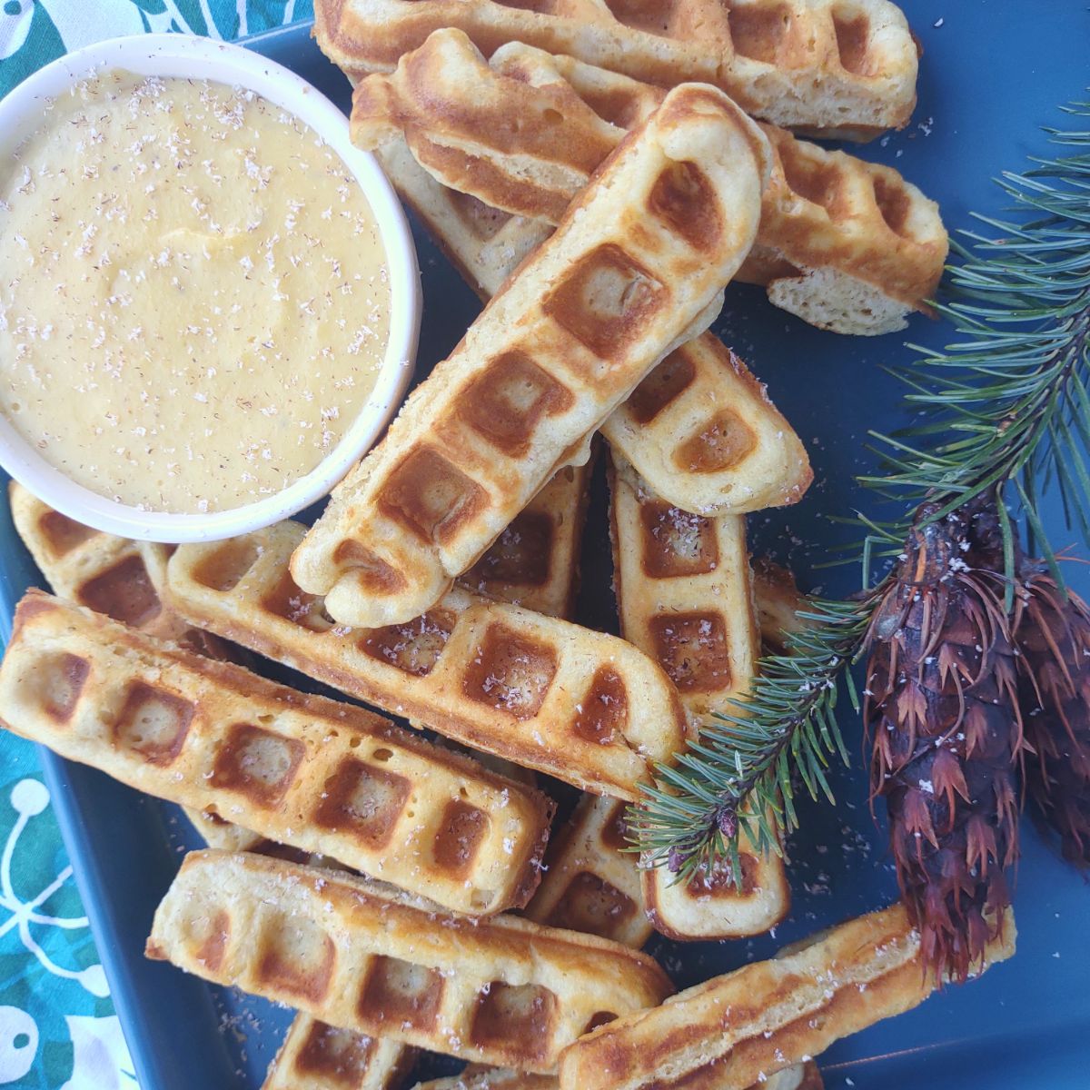 Egg nog waffle sticks surrounding a bowl of egg nog dipping sauce.