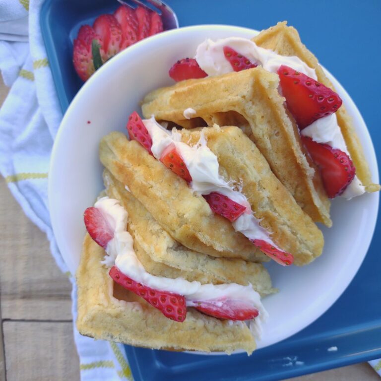 Triangle shaped waffles that are stuffed with a cream cheese filling and fresh strawberries